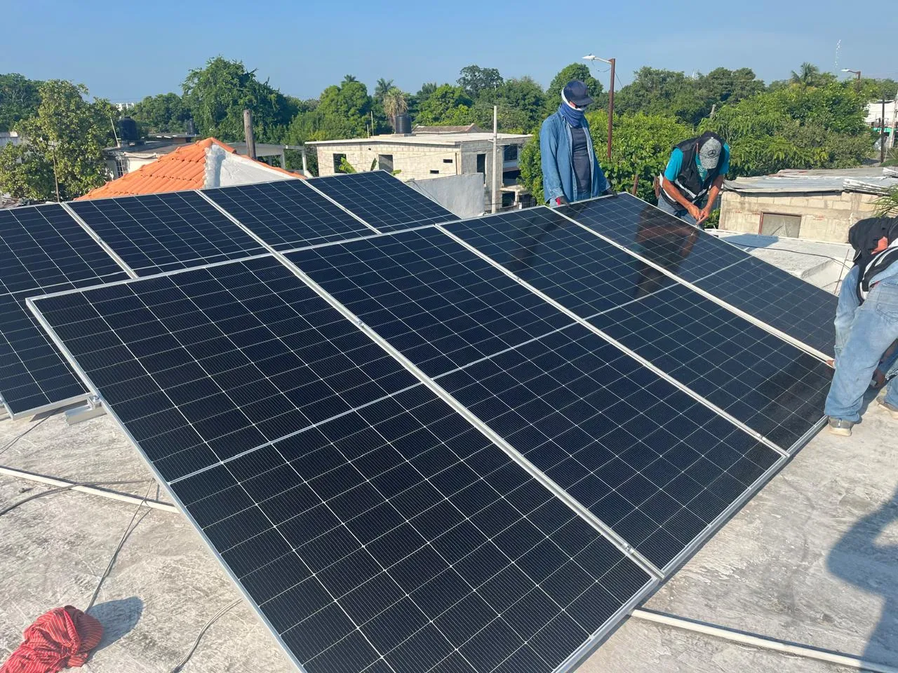 Instaladores de Solar Performance conectando un sistema de paneles solares sobre un techo de concreto